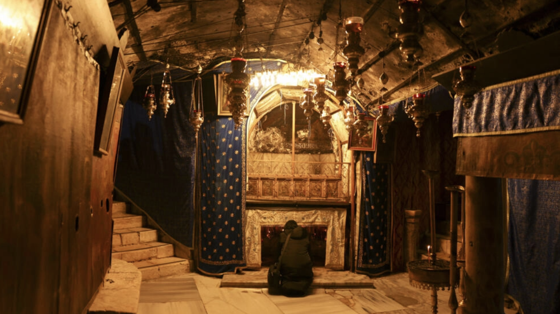 Một du khách đơn độc cầu nguyện tại hang động nơi Chúa Jesus sinh ra - Ảnh: AFP