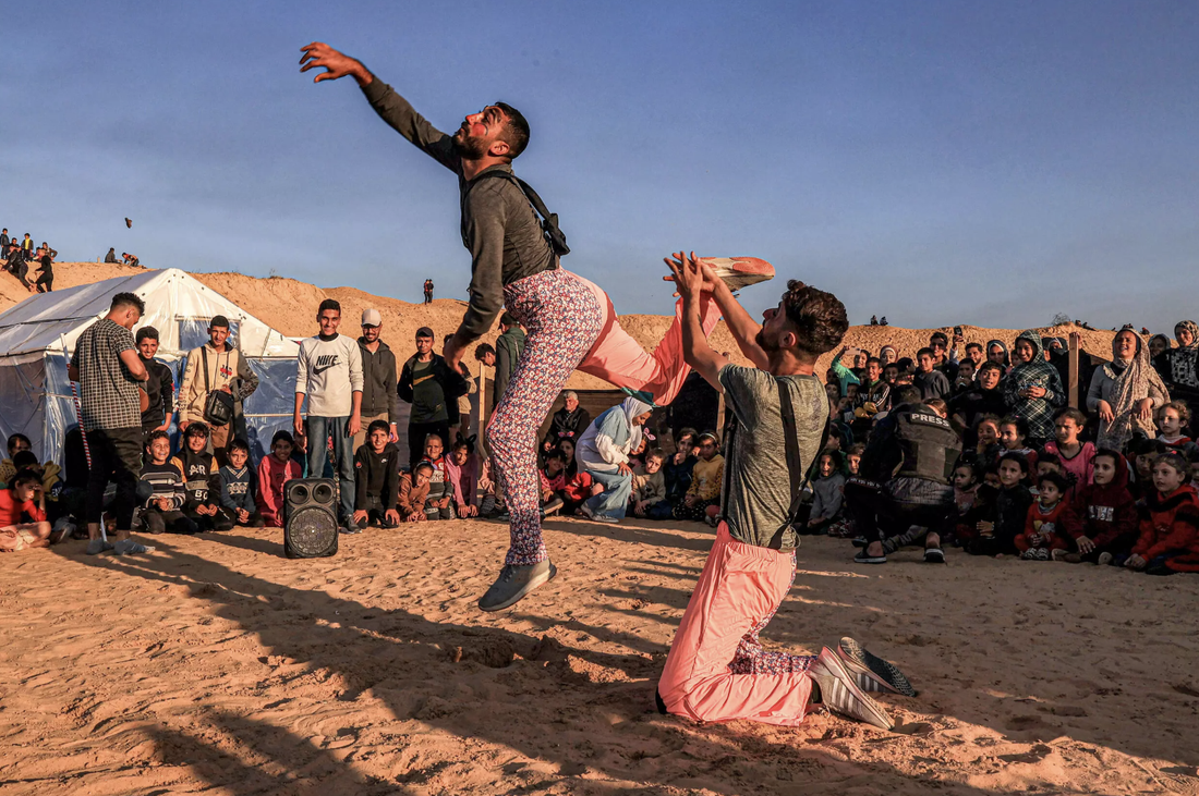 Những đứa trẻ tại Dải Gaza chăm chú xem các nghệ sĩ tình nguyện biểu diễn - Ảnh: AFP