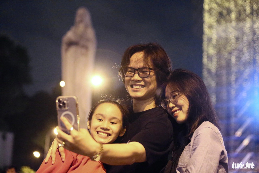 Gia đình của anh Nam lưu lại kỷ niệm đêm Noel 2023 cùng hình ảnh nhà thờ Đức Bà và tượng Đức Bà Hòa Bình - Ảnh: PHƯƠNG QUYÊN