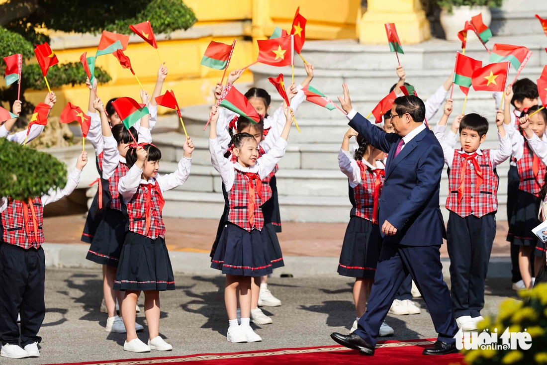 Thủ tướng Phạm Minh Chính vẫy tay chào các em thiếu nhi Hà Nội khi rảo bước trên thảm đỏ, đến nơi đón Thủ tướng Belarus Roman Golovchenko - Ảnh: NGUYỄN KHÁNH