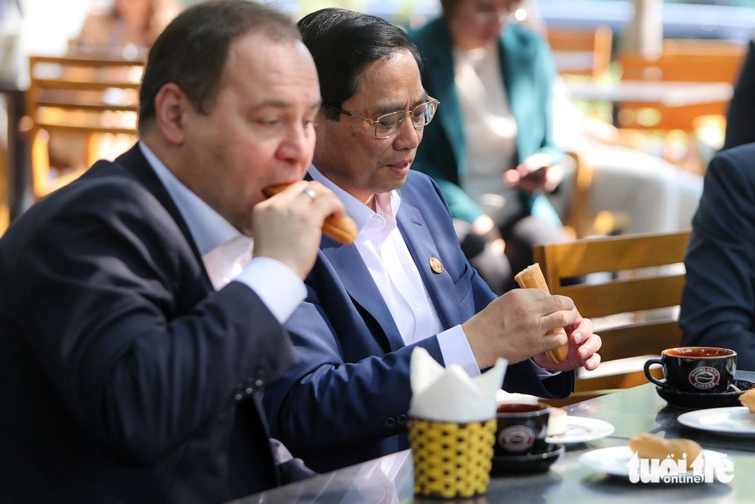 Thủ tướng Phạm Minh Chính và Thủ tướng Belarus Roman Golovchenko ăn bánh mì nhân thịt gà Việt Nam - Ảnh: NGUYỄN KHÁNH