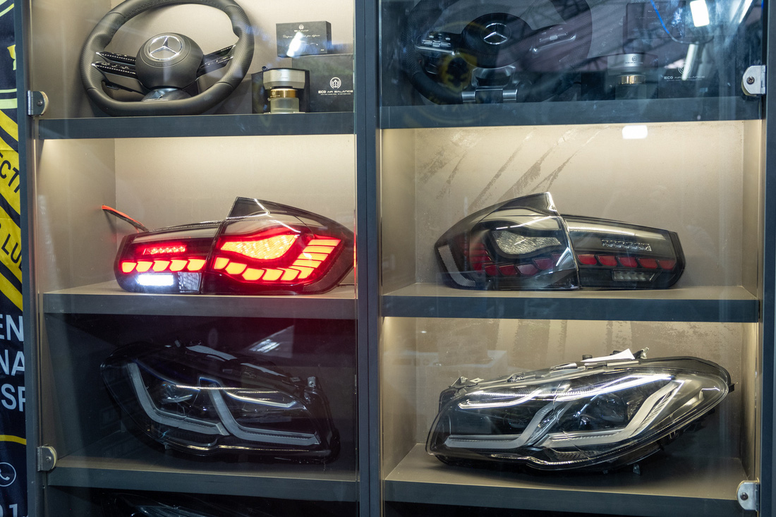 Một quầy trưng bày đèn pha và đèn hậu độ theo xe đời mới dành cho BMW 5-Series đời cũ, cùng vô lăng dành cho các mẫu xe Mercedes-Benz - Ảnh: QUỐC MINH - BTC