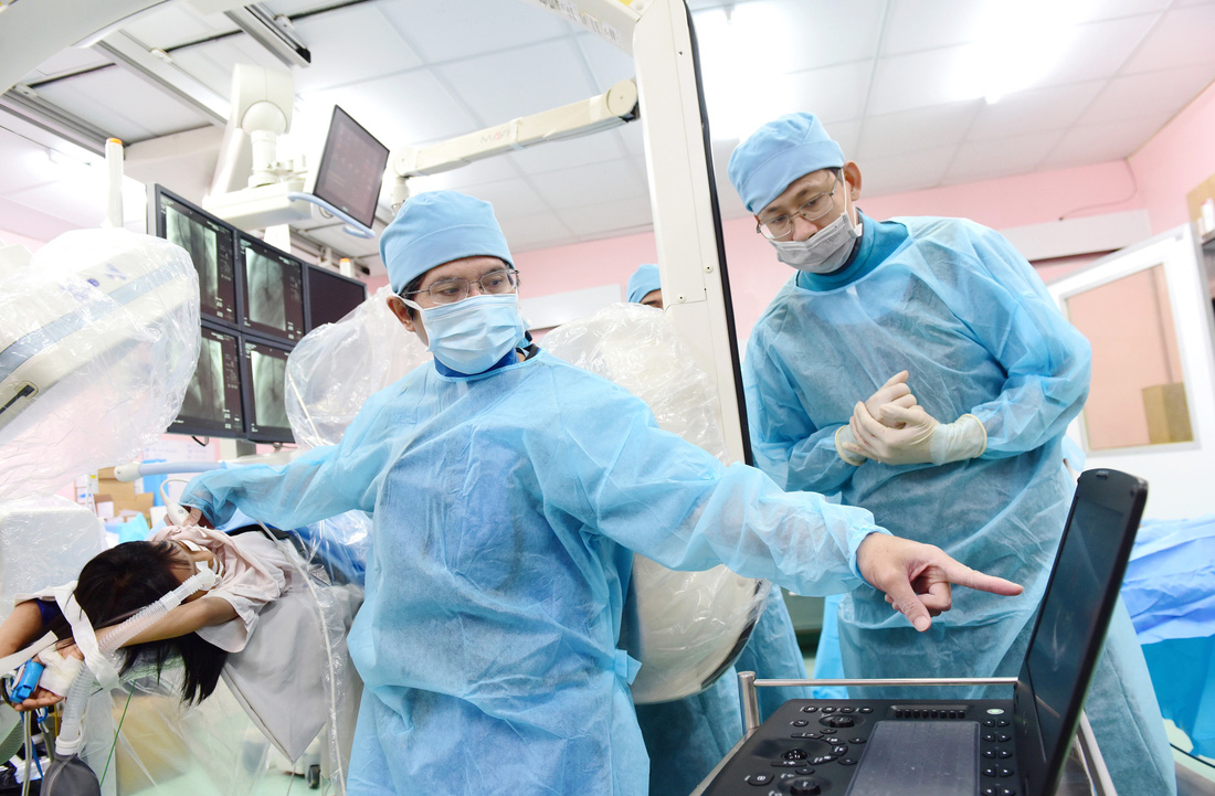 Bác sĩ Đỗ Nguyên Tín (trái) đang khám cho một bệnh nhi và truyền nghề cho đồng nghiệp trẻ - Ảnh: DUYÊN PHAN