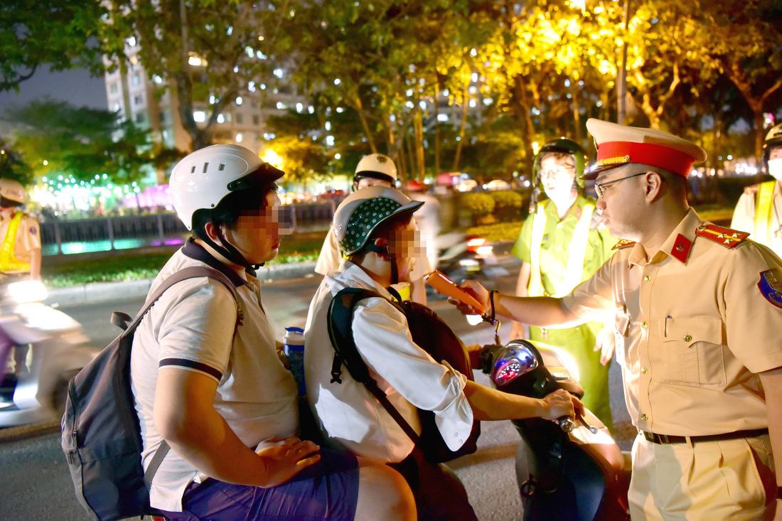 Cảnh sát giao thông phối hợp cảnh sát trật tự đo nồng độ cồn các lái xe máy trên đường Hoàng Sa, quận 1, TP.HCM tối 11-4 - Ảnh: T.T.D.