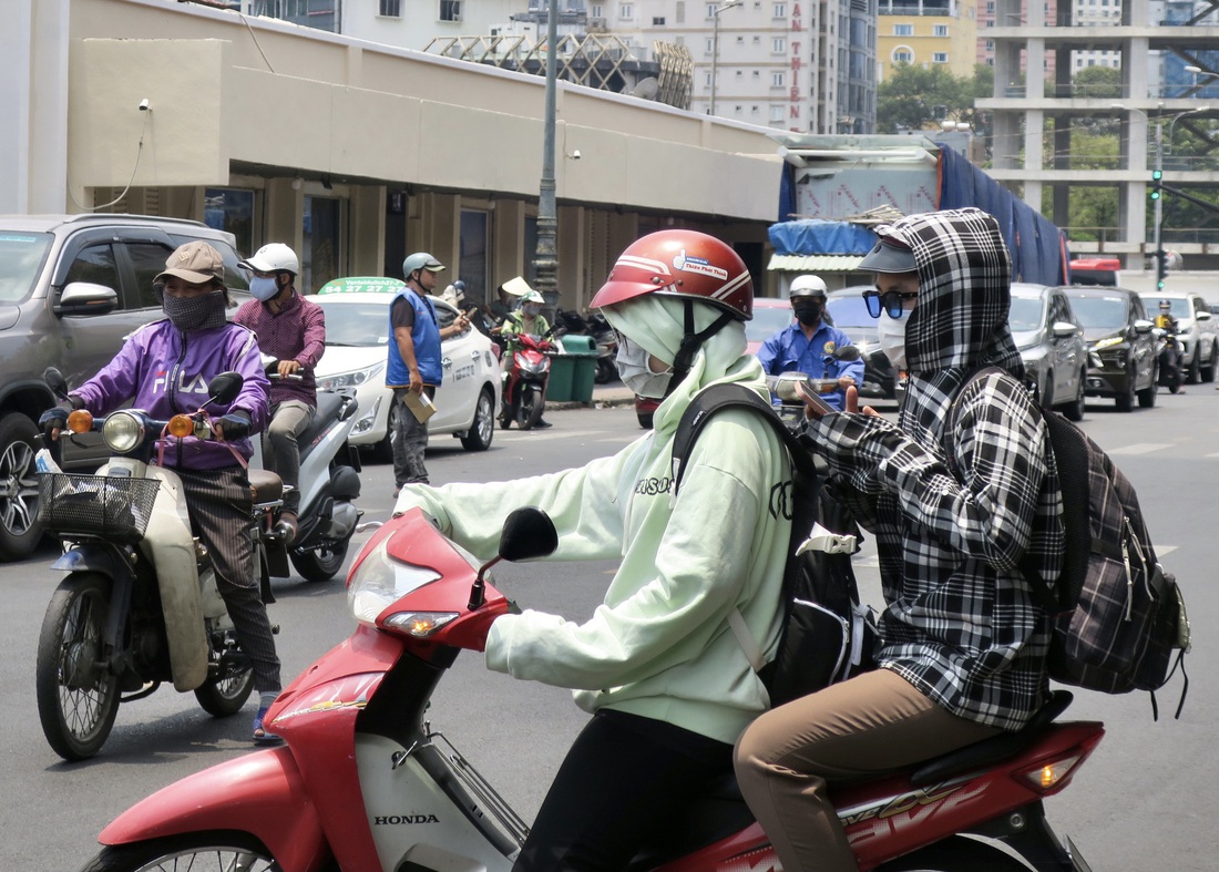 Hai bạn trẻ mặc áo chống nóng khi đi trên đường ở trung tâm TP.HCM trưa 5-5 - Ảnh: T.T.D.