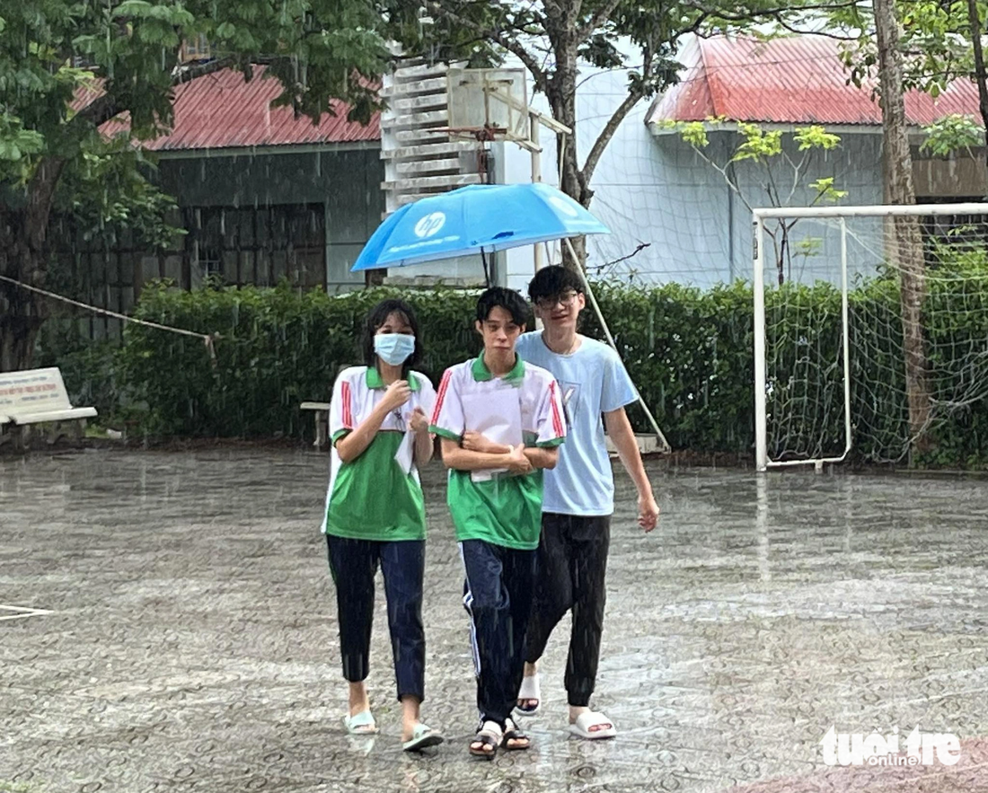 Các bạn học sinh 12 đến điểm thi đúng giờ dù trời mưa khá lớn - Ảnh: LAN NGỌC