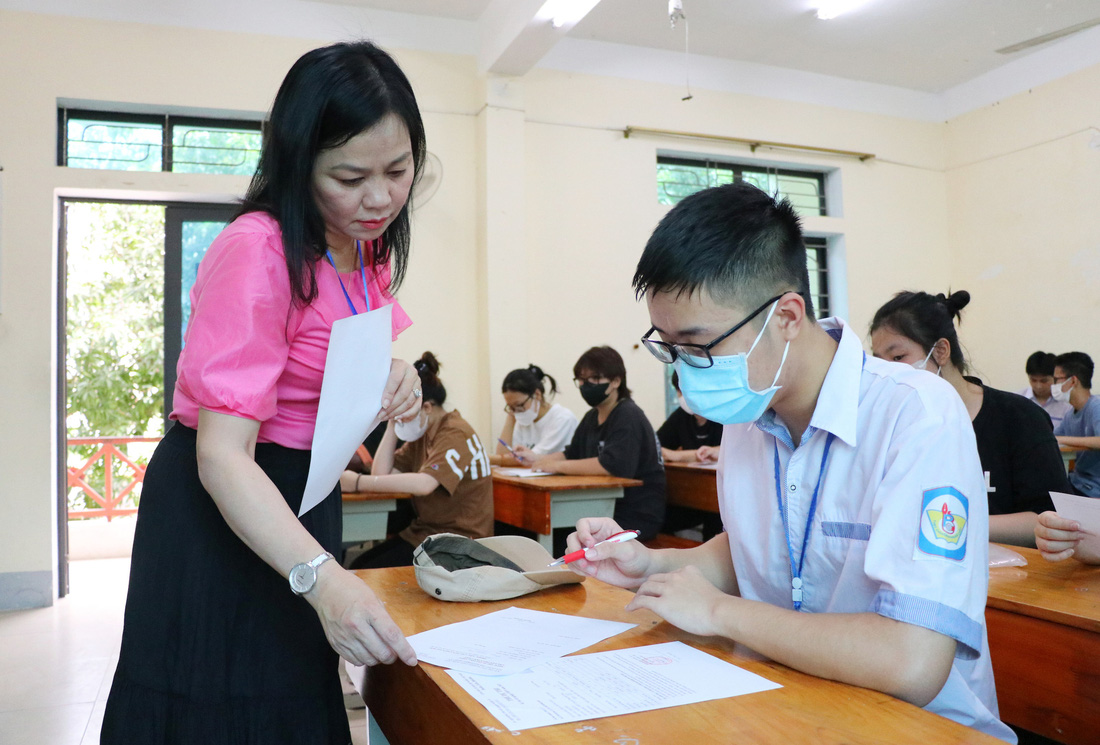 Giám thị đối chiếu thẻ dự thi và căn cước công dân của thí sinh tại điểm thi Trường THPT chuyên Phan Bội Châu, Nghệ An - Ảnh: DOÃN HÒA