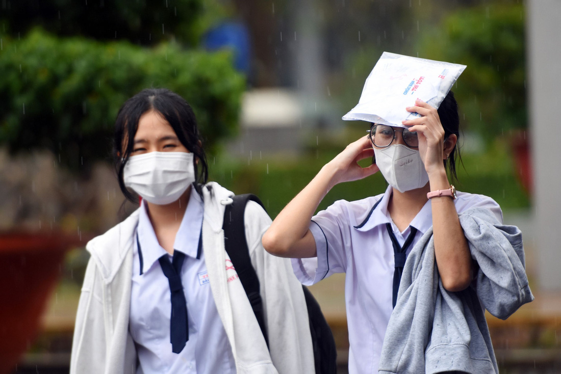 Các thí sinh tại điểm thi Trường THPT Trấn Biên (TP Biên Hòa, Đồng Nai) đội mưa rời phòng thi sau khi kết thúc môn toán - Ảnh: A LỘC