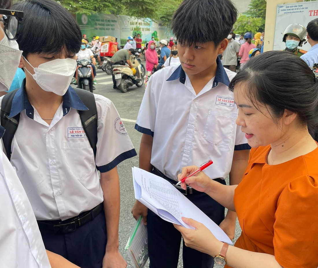 Cô Hồng Mơ, Trường THCS Lê Văn Tám, quận Bình Thạnh đang điểm danh học sinh tại cổng trường - Ảnh: LIÊN CHI