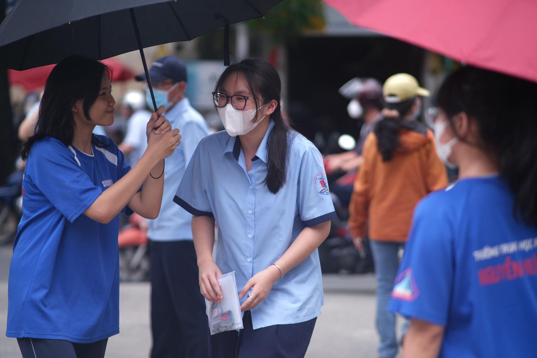 Các em học sinh trường THPT Nguyễn Hữu Huân (TP Thủ Đức) hỗ trợ và động viên thí sinh thi đi thi - Ảnh: NGỌC PHƯỢNG