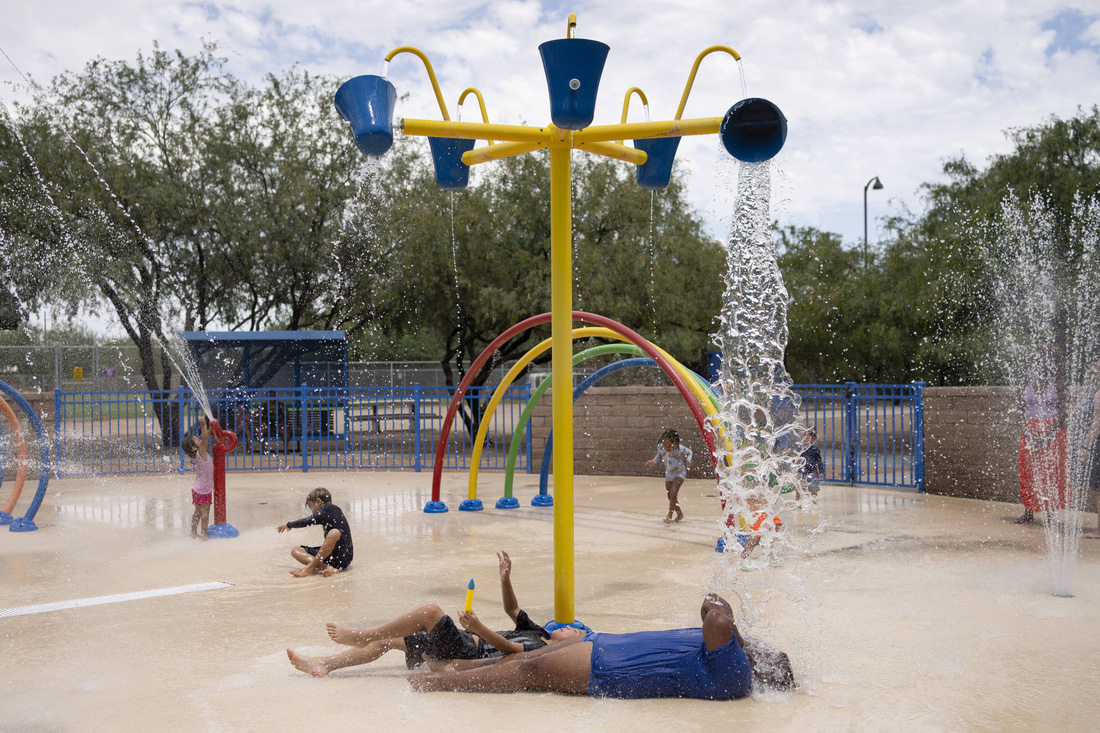 Người dân giải nóng bằng cách nằm tại khu trò chơi nước ở công viên tưởng niệm Brandi Fenton của thành phố Tucson, Arizona ngày 15-7 - Ảnh: AFP
