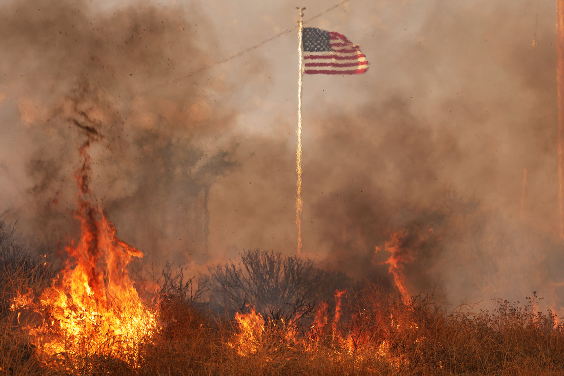 Quốc kỳ Mỹ bay giữa đám cháy ngày 14-7 tại thung lũng Moreno (hạt Riverside, bang California). Đám cháy là hệ quả của làn sóng nhiệt đang quét qua nước Mỹ - Ảnh: AFP