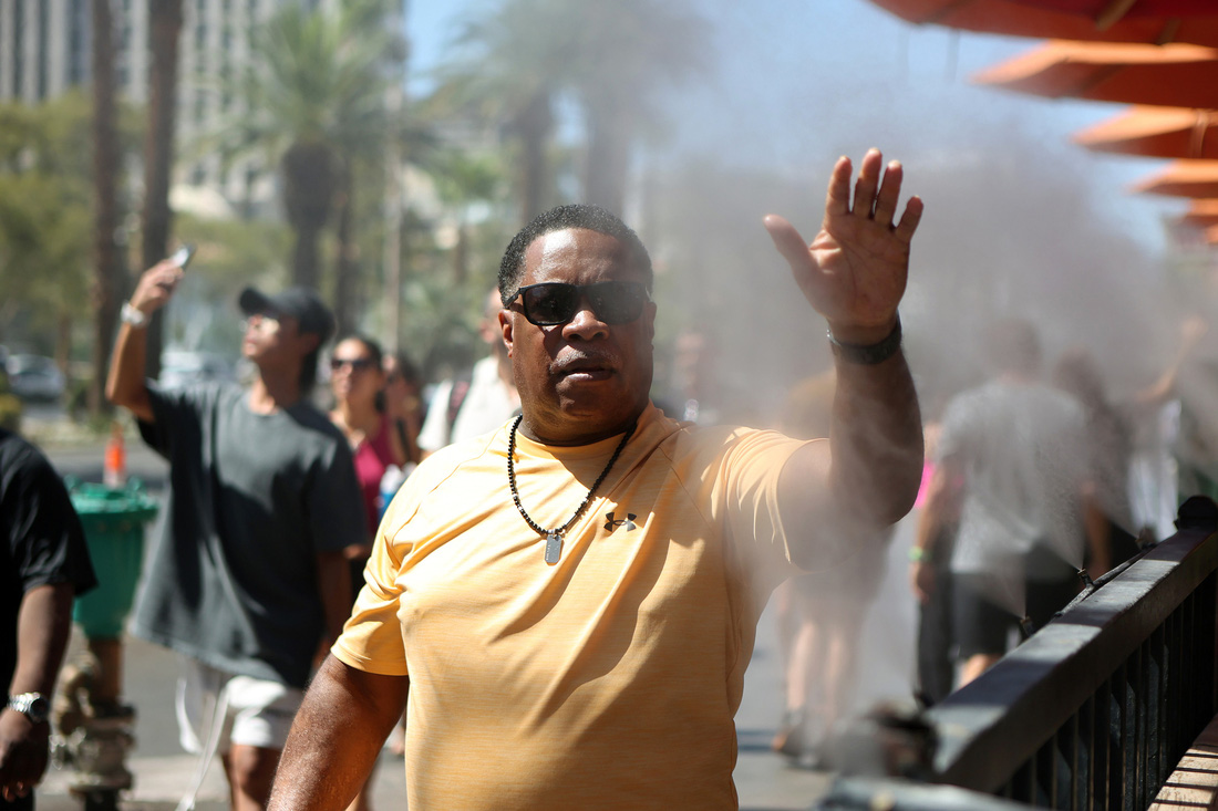 Người đi đường giải mát bằng cách đưa tay qua vòi phun sương tại thành phố Las Vegas (bang Nevada) hôm 14-7 - Ảnh: AFP