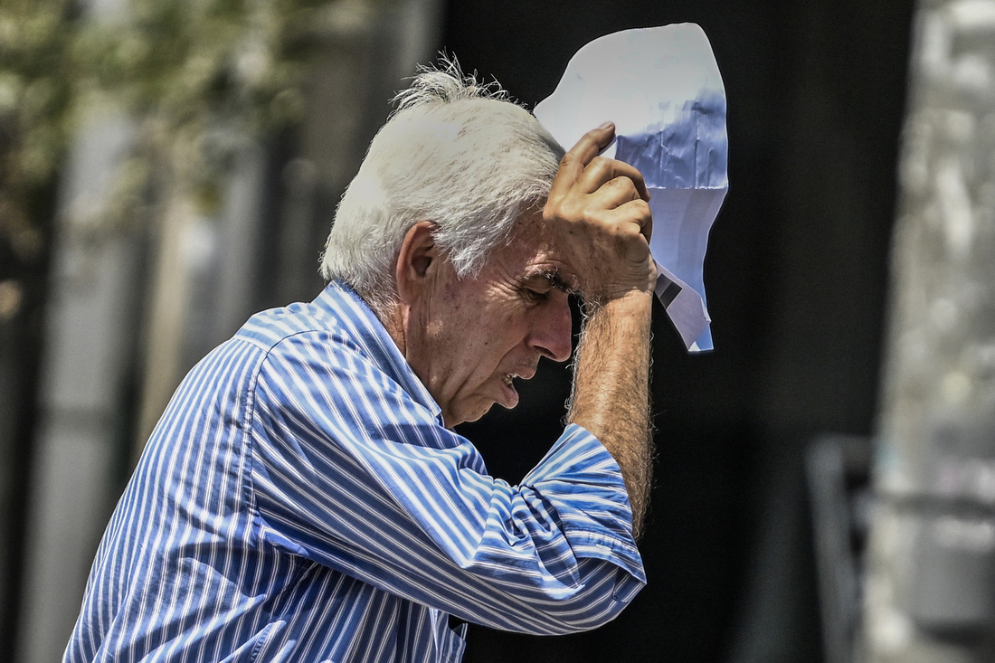 Một người cao tuổi phải nhăn mặt bởi cái nóng của thủ đô Athens, Hy Lạp ngày 13-7 - Ảnh: AFP