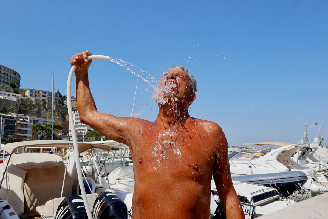 Một người đàn ông tại thành phố Napoli (Ý) dùng vòi nước tắm giải nóng - Ảnh: REUTERS