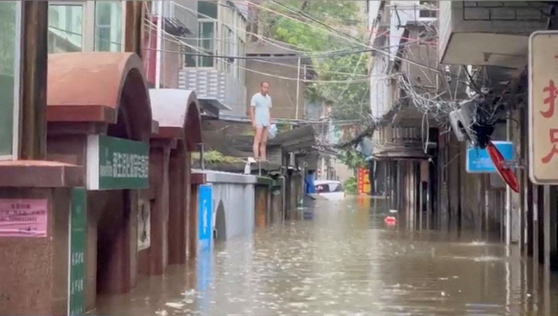 Một người dân bị mắc kẹt do nước lũ ở thành phố Phúc Châu - Ảnh: REUTERS