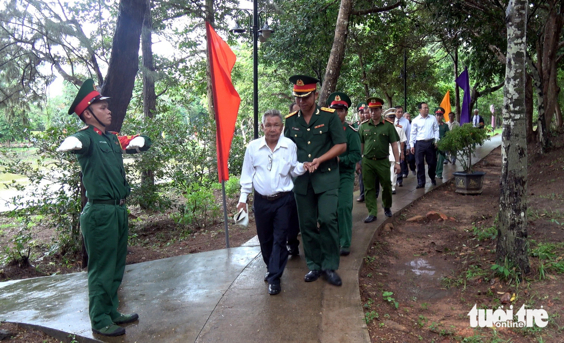 Cựu tù chính trị Lê Văn Lợi đến từ Bến Tre được một sĩ quan trẻ dìu đi thăm mộ, thắp hương cho những đồng đội đã ngã xuống - Ảnh: ĐÔNG HÀ 