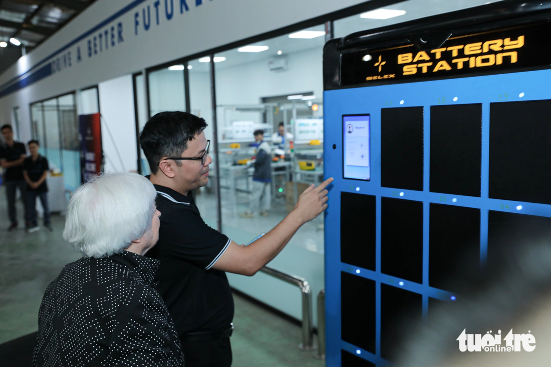 Bộ trưởng Yellen đi dạo tham quan dây chuyền sản xuất lắp ráp xe máy điện và đang quan sát hệ thống trạm ATM pin cho xe máy điện của Selex - Ảnh: DANH KHANG