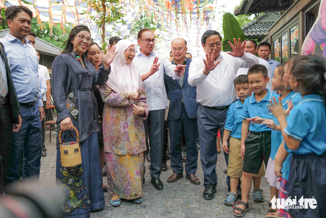 Thủ tướng Phạm Minh Chính và Thủ tướng Malaysia Anwar Ibrahim cùng hai phu nhân trò chuyện với các em nhỏ tại đường  sách - Ảnh: NGUYỄN KHÁNH