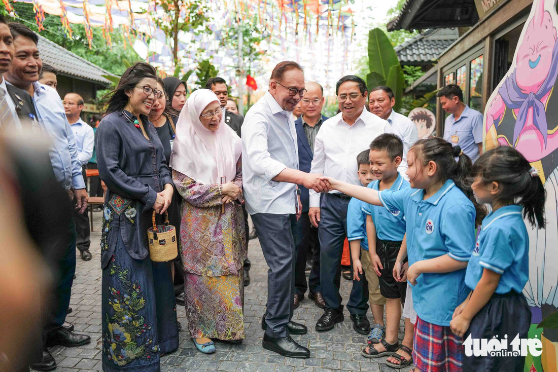 Thủ tướng Malaysia Anwar Ibrahim bắt tay trò chuyện với một em nhỏ tại đường sách Hà Nội - Ảnh: NGUYỄN KHÁNH