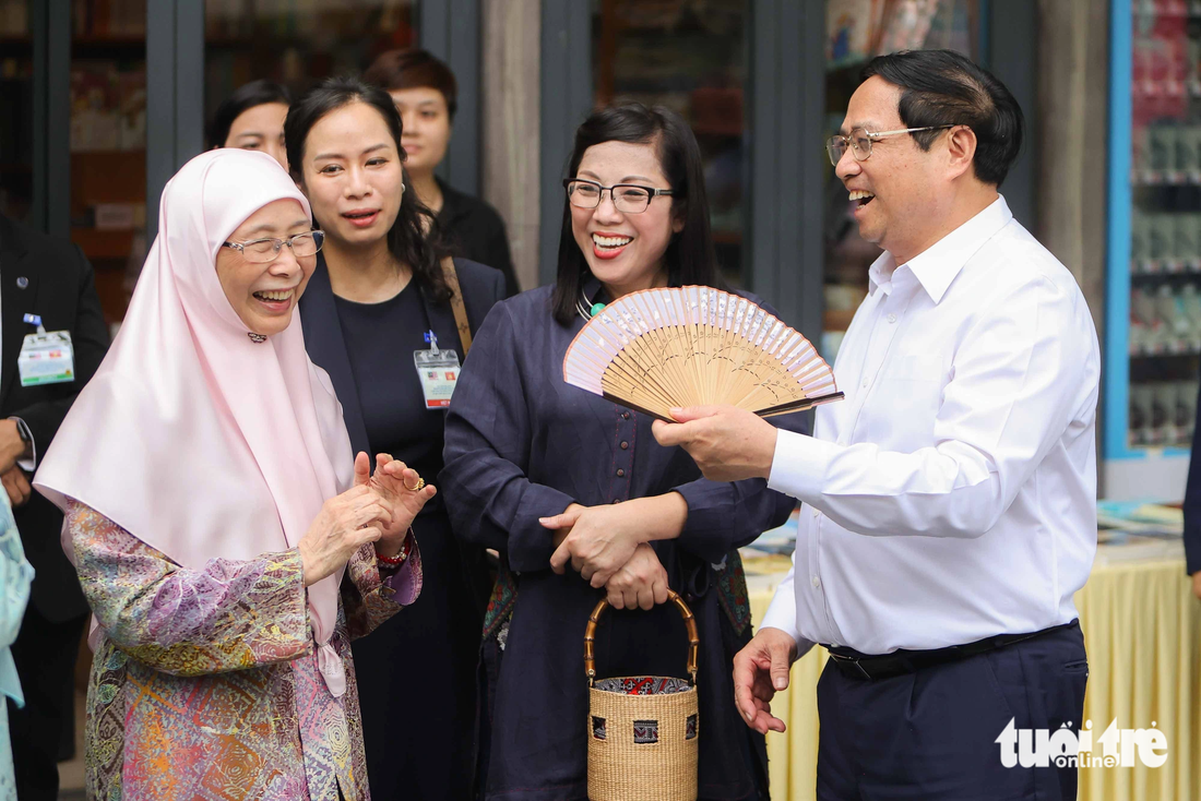 Phu nhân Thủ tướng Malaysia bật cười và cảm ơn khi Thủ tướng Phạm Minh Chính dùng quạt để quạt mát cho bà và phu nhân Lê Thị Bích Trân - Ảnh: NGUYỄN KHÁNH