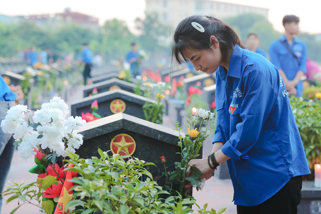 Từ 17h chiều, bạn Trịnh Thu Hương, 19 tuổi, sinh viên Trường đại học Công nghiệp Hà Nội, cùng các bạn đoàn viên đã đến nghĩa trang TP Hà Nội để thay những bó hoa trắng tại từng phần mộ liệt sĩ, chuẩn bị nến để thắp vào buổi tối. Đây cũng là nhiệm vụ “đặc biệt” mà Hương thực hiện gần 10 năm nay mỗi dịp 27-7 - Ảnh: DANH KHANG