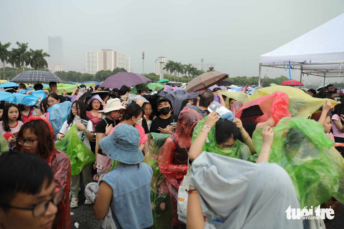 17h35 trời bất chợt đổ mưa trong khi khán giả chưa vào sân. Nhiều người chấp nhận mua áo mưa với giá 30.000 đồng/ chiếc - Ảnh: DANH KHANG