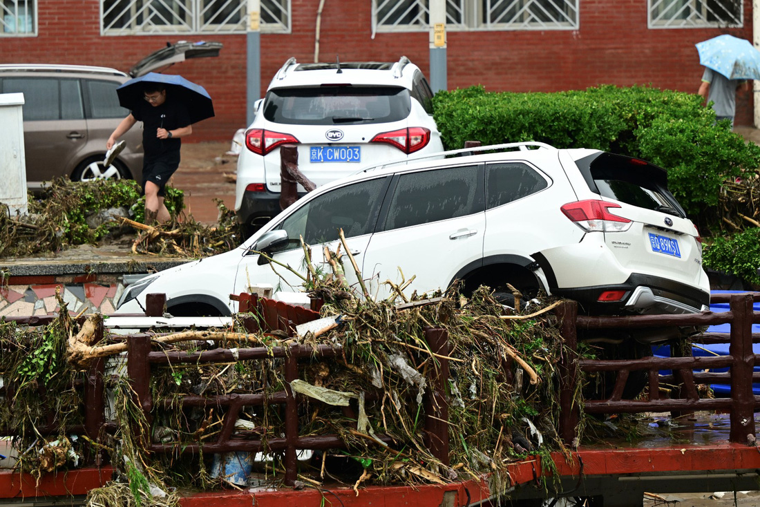 Xe ô tô mắc kẹt sau lũ cuốn - Ảnh: AFP