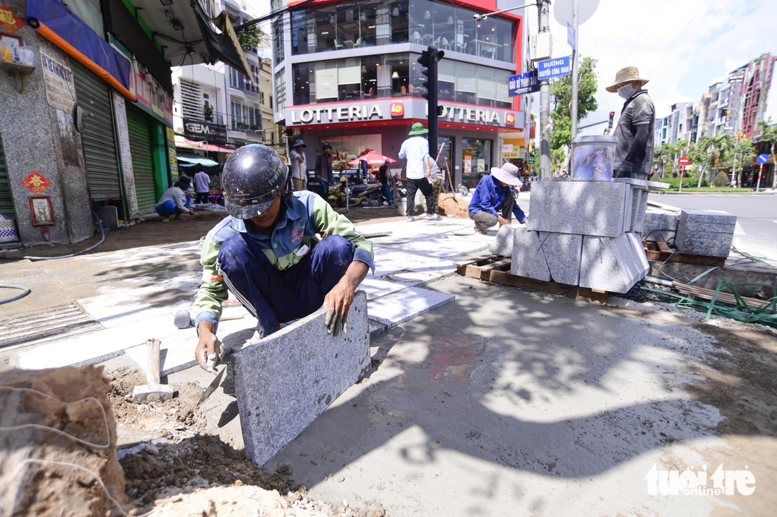Các công nhân đang cấp tốc thi công lát đá vỉa hè trên đường Phan Xích Long - Ảnh: QUANG ĐỊNH