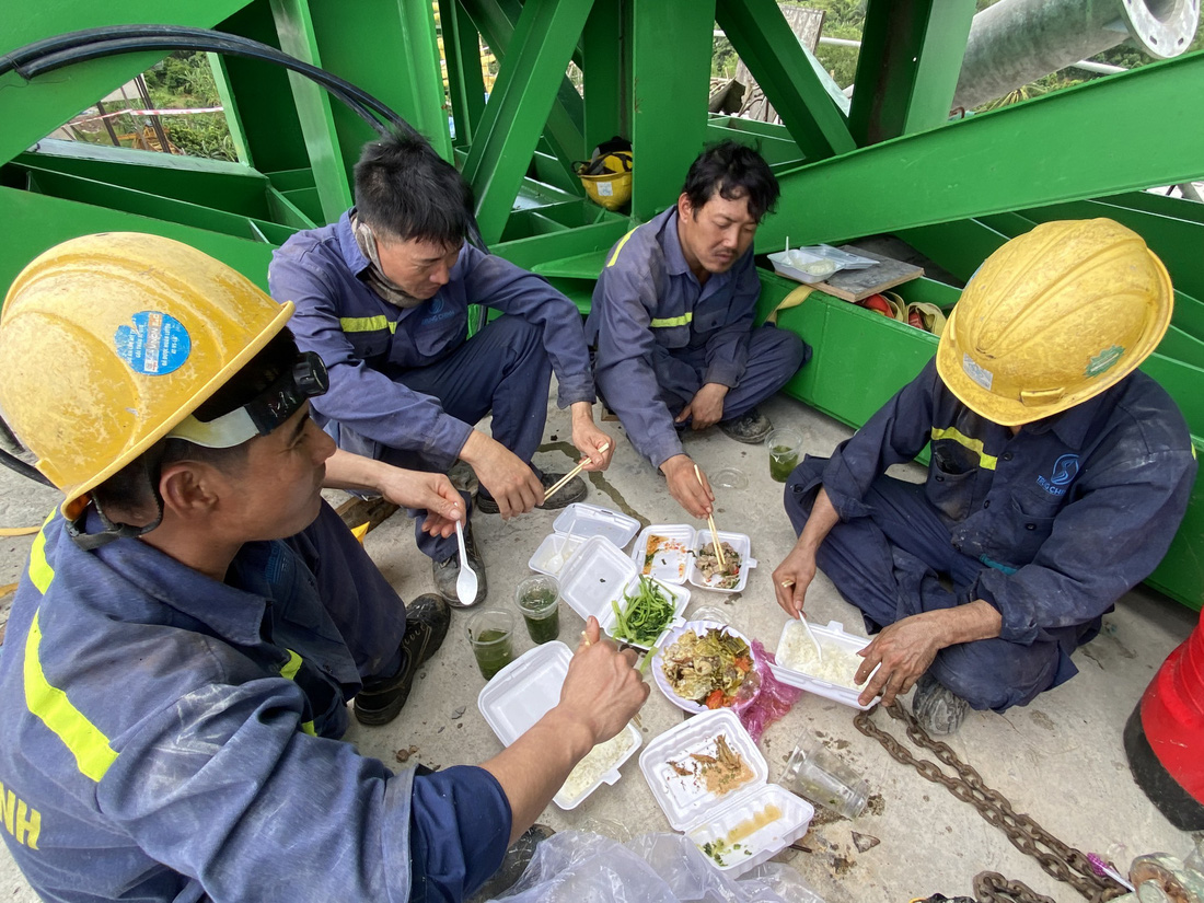 Để công trình kịp tiến độ, các công nhân phải thay nhau làm việc liên tục 3 ca. Trong ảnh: công nhân tranh thủ ăn trưa ngay tại công trường để chuẩn bị làm việc tiếp - Ảnh: M.T.