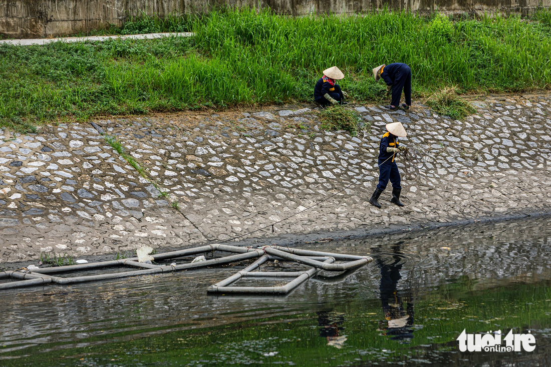 Công nhân thoát nước làm việc bên bờ sông Tô Lịch - Ảnh: QUANG THẾ