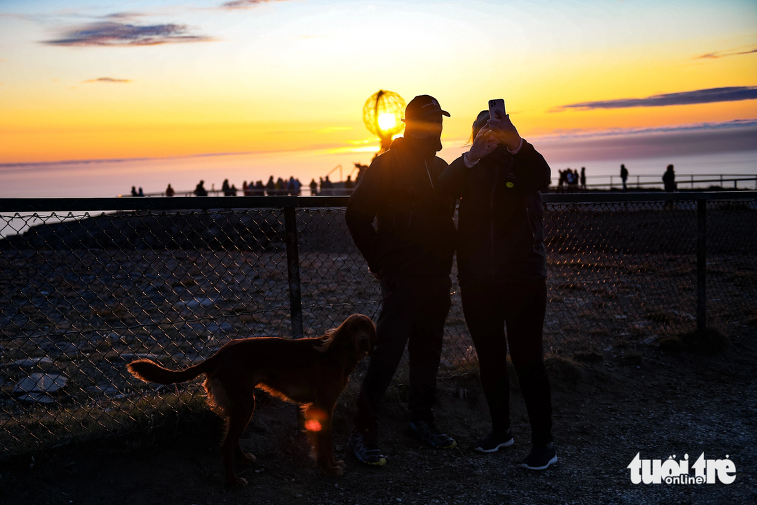 Một cặp đôi cùng chú chó chụp ảnh với ánh Mặt trời giữa đêm - Ảnh: NAM TRẦN