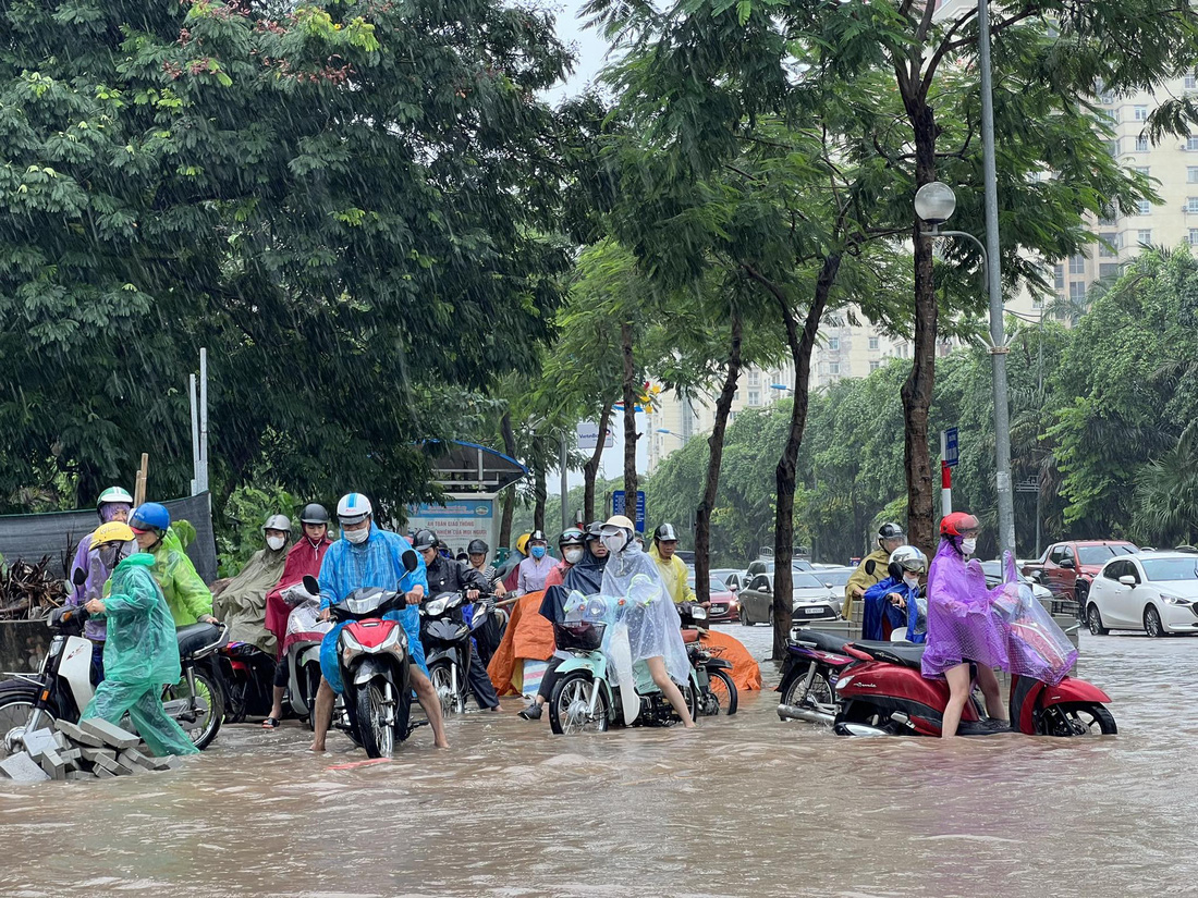 Do ngập sâu, đường phố ùn tắc nên nhiều người đi xe máy phải leo lên vỉa hè - Ảnh: PHẠM TUẤN