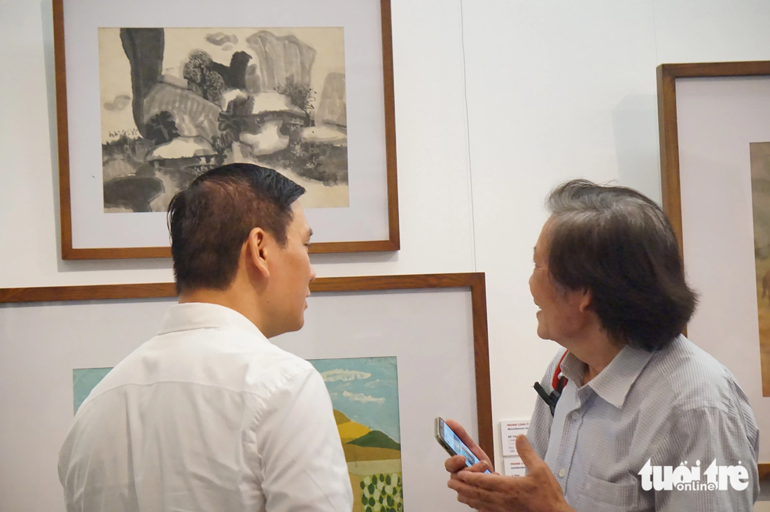 Họa sĩ Đỗ Đức (phải) trò chuyện với người yêu tranh về bức tranh của mình (bên trên) treo tại triển lãm Đất nước tôi - Ảnh: T.ĐIỂU