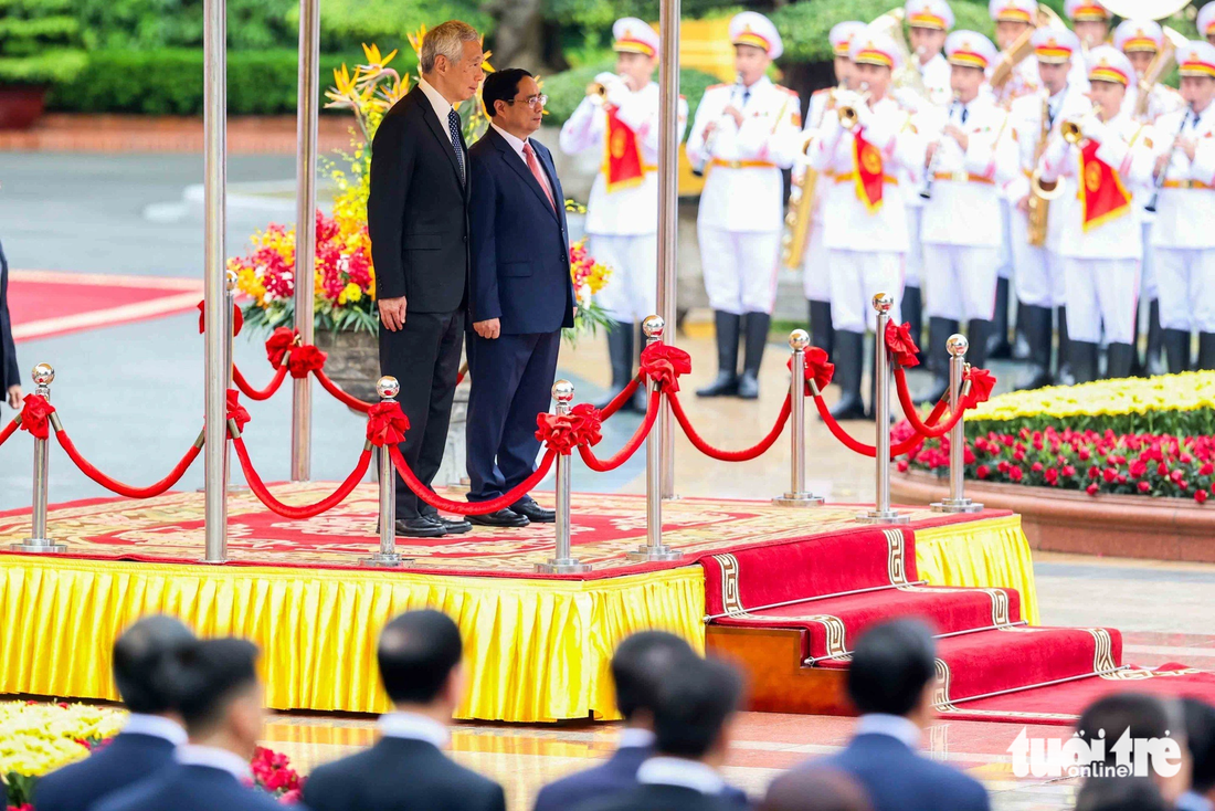 Thủ tướng Việt Nam và Singapore bước lên bục danh dự, quân nhạc lần lượt cử quốc thiều hai nước - Ảnh: NGUYỄN KHÁNH