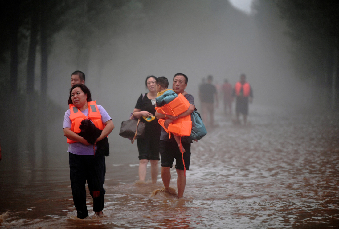 Người dân đi qua những con đường bị ngập nước sau mưa lớn ở Trác Châu hôm 1-8 - Ảnh: REUTERS