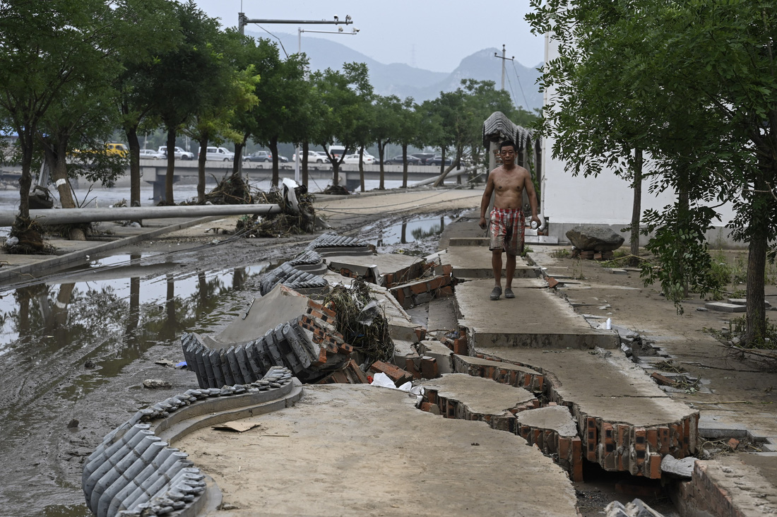 Một người dân địa phương đi trên con đường bị nứt vỡ do ngập lụt ở miền bắc Trung Quốc - Ảnh: AFP