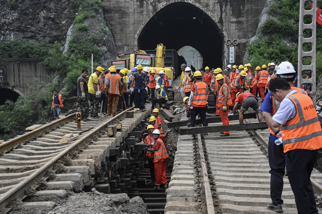 Công nhân đang sửa lại một đoạn đường sắt bị hư hại do mưa lũ ở Trung Quốc - Ảnh: AFP
