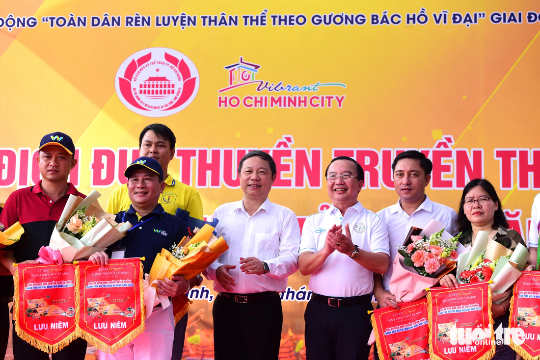 Ông Dương Anh Đức, phó chủ tịch UBND TP.HCM (giữa) và ông Trần Thế Thuận, giám đốc Sở Văn hóa và Thể thao TP.HCM trao cờ lưu niệm cho các đội đua