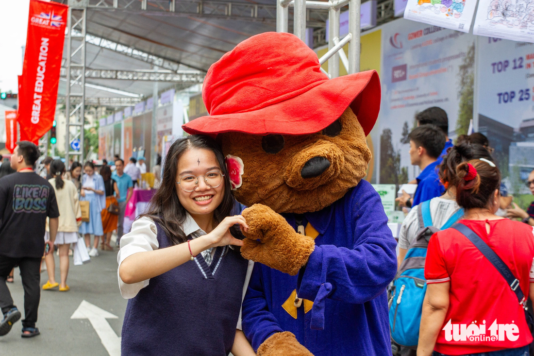 Khách tham quan chụp ảnh lưu niệm cùng linh vật một trường đại học Anh - Ảnh: NGỌC ĐỨC