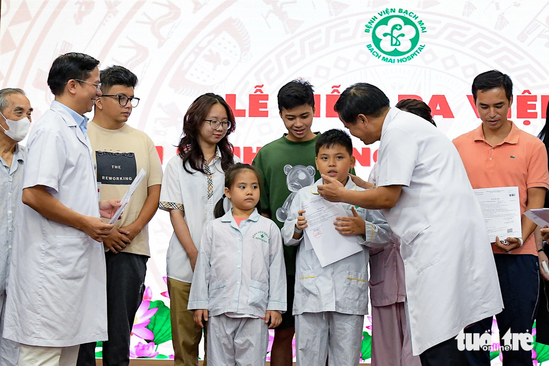 Ông Đào Xuân Cơ, giám đốc Bệnh viện Bạch Mai, tặng quà chúc mừng bệnh nhân được ra viện - Ảnh: NAM TRẦN