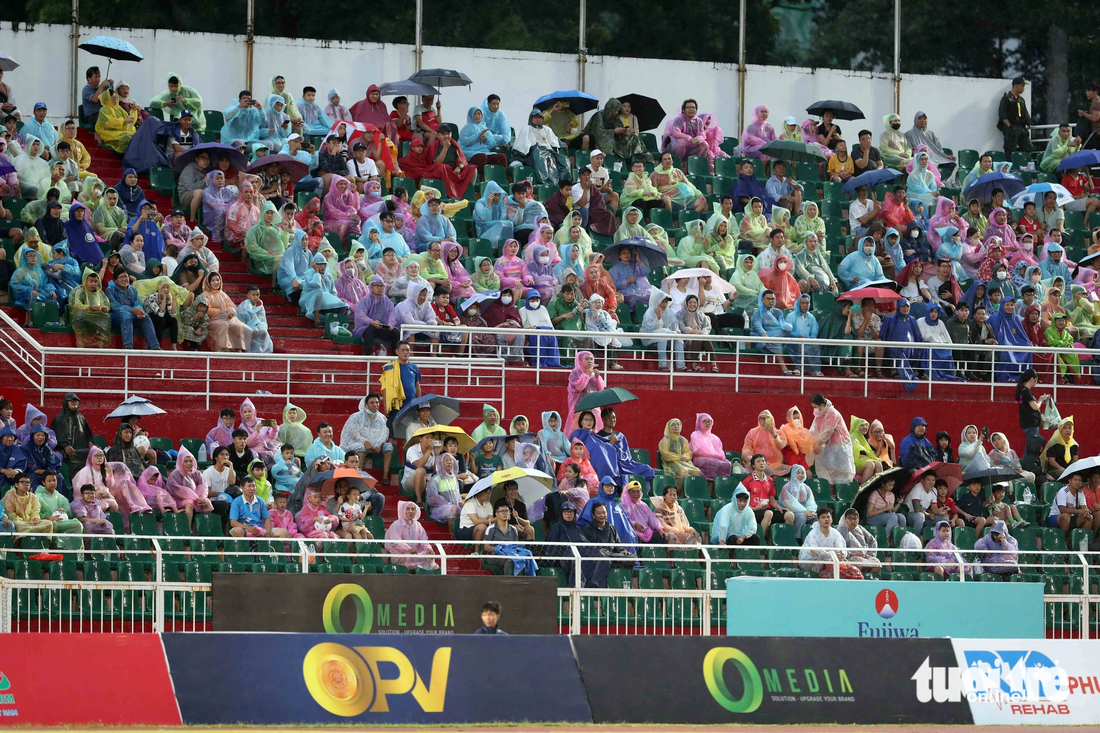 Khán giả đội mưa xem trận đấu - Ảnh: N.K