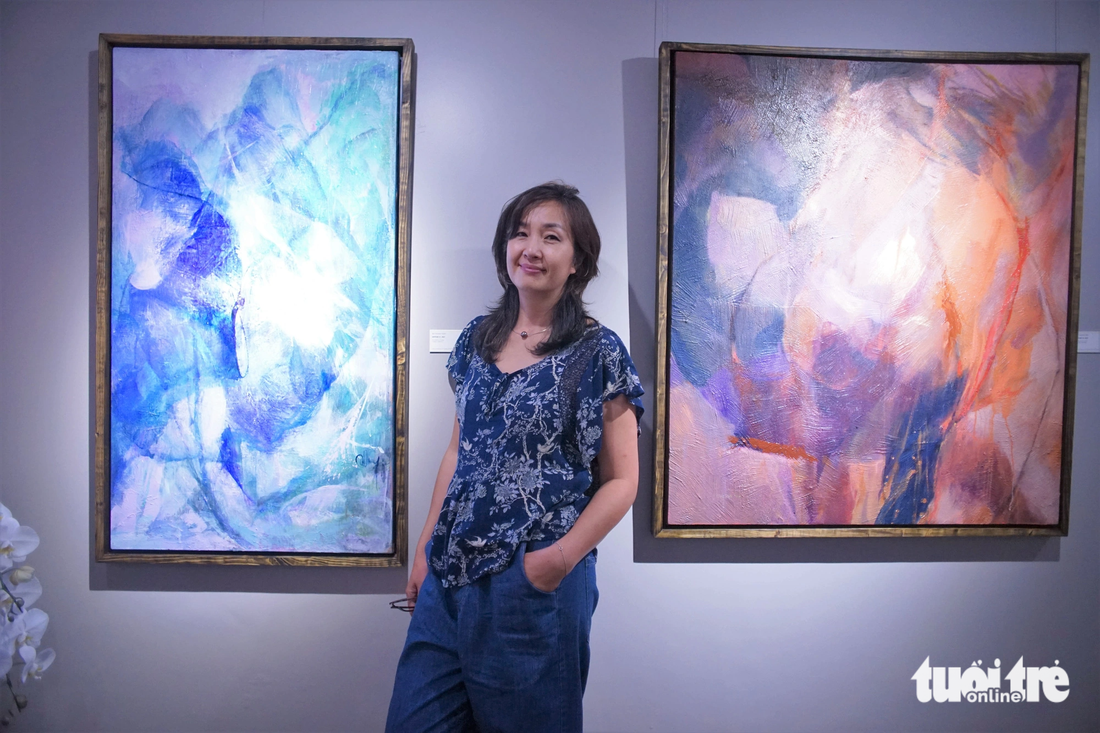 Họa sĩ Bùi Thanh Thủy bên tác phẩm của mình tại triển lãm Ngoạn tình - Ảnh: H.VY