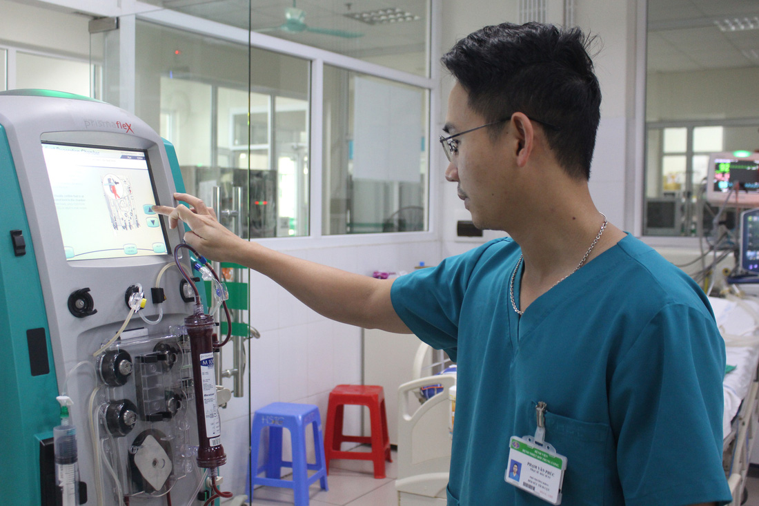 Bác sĩ Phạm Văn Phúc theo dõi tình trạng bệnh nhân sốt xuất huyết đang điều trị tại Bệnh viện Bệnh nhiệt đới Trung ương - Ảnh: DƯƠNG LIỄU