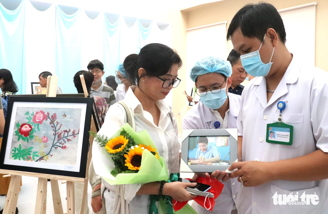 Bệnh viện An Bình bất ngờ tặng chị Đoàn Nguyên Thùy bức ảnh chụp anh Phạm Minh Đức (chồng chị Thùy) đang vẽ tranh bằng tay trái lúc còn sống - Ảnh: XUÂN MAI