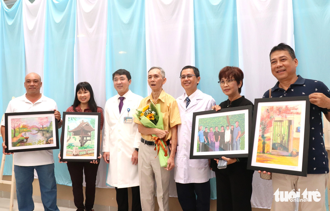 Bệnh nhân Lê Cao Nguyên cùng ông Hồ Hải Trường Giang - giám đốc Bệnh viện An Bình - và người thân chụp ảnh kỷ niệm những bức tranh do chính bệnh nhân vẽ trong thời gian điều trị sau tai biến mạch máu não tại Bệnh viện An Bình - Ảnh: XUÂN MAI