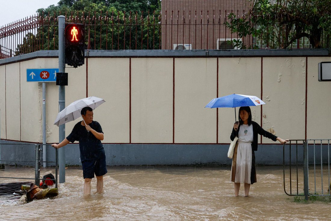 Người dân phải bám vào các tay vịn để dò bước đi do dòng nước mưa quá mạnh ngày 8-9 ở Hong Kong - Ảnh: REUTERS