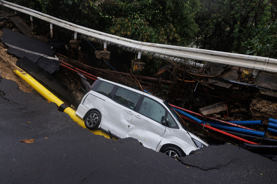 Một chiếc xe bị lọt hố do lở đường ở Hong Kong - Ảnh: REUTERS