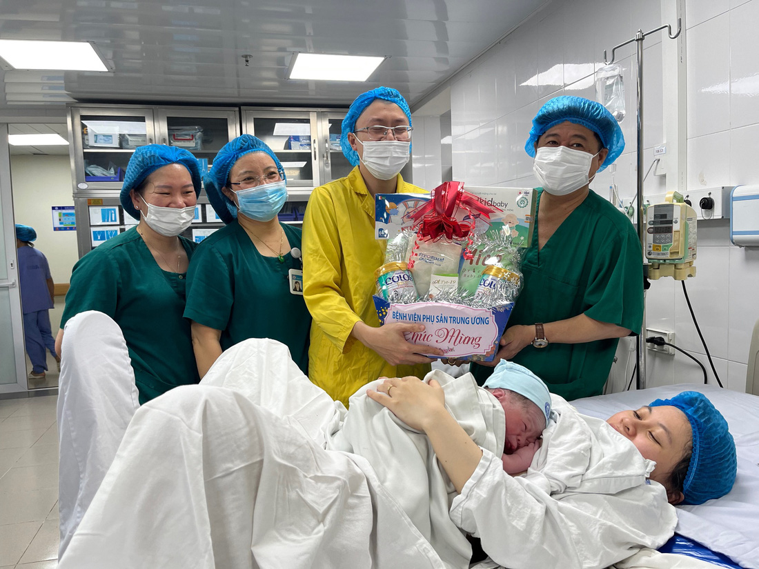 Ông Đinh Anh Tuấn (bìa phải) tặng quà cho gia đình bé Nghị ngay sau khi đón bé chào đời - Ảnh: HỒNG HÀ