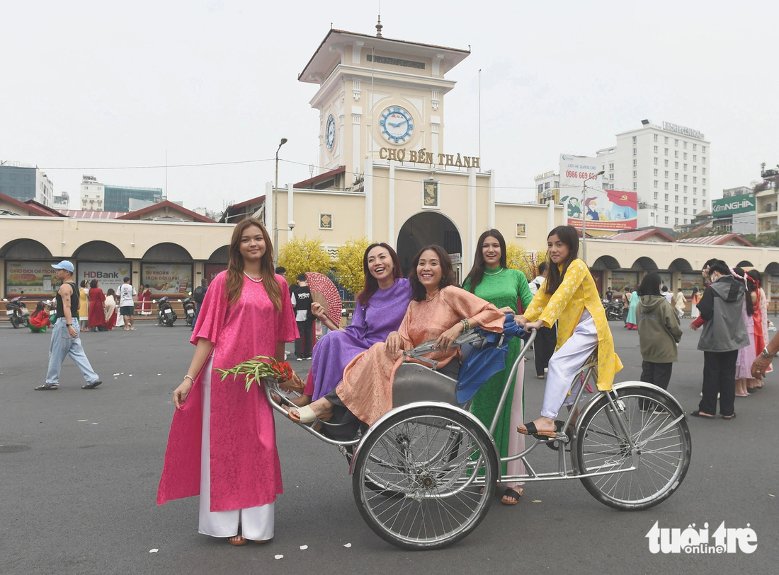 Một nhóm Việt kiều cùng gia đình thuê xe xích lô chụp hình kỷ niệm tại chợ Bến Thành